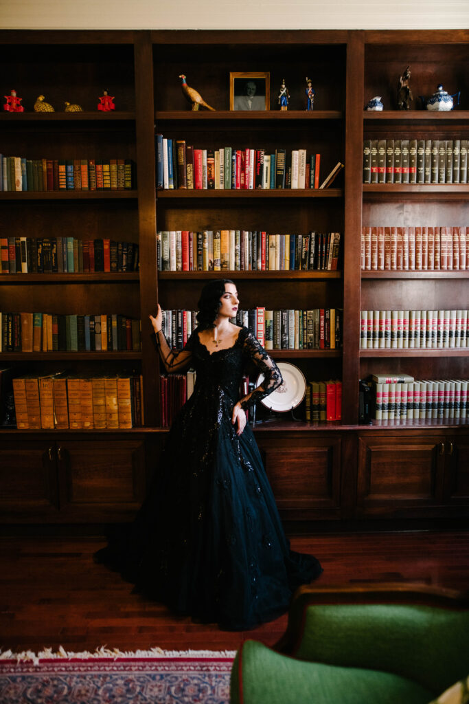 Bride wearing a black wedding dress posed in a library.
