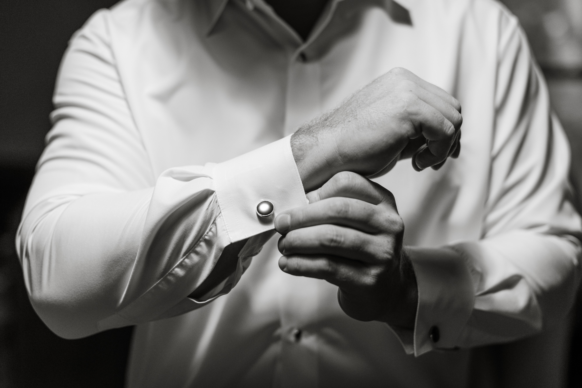 Groom inserting cufflinks black and white photo
