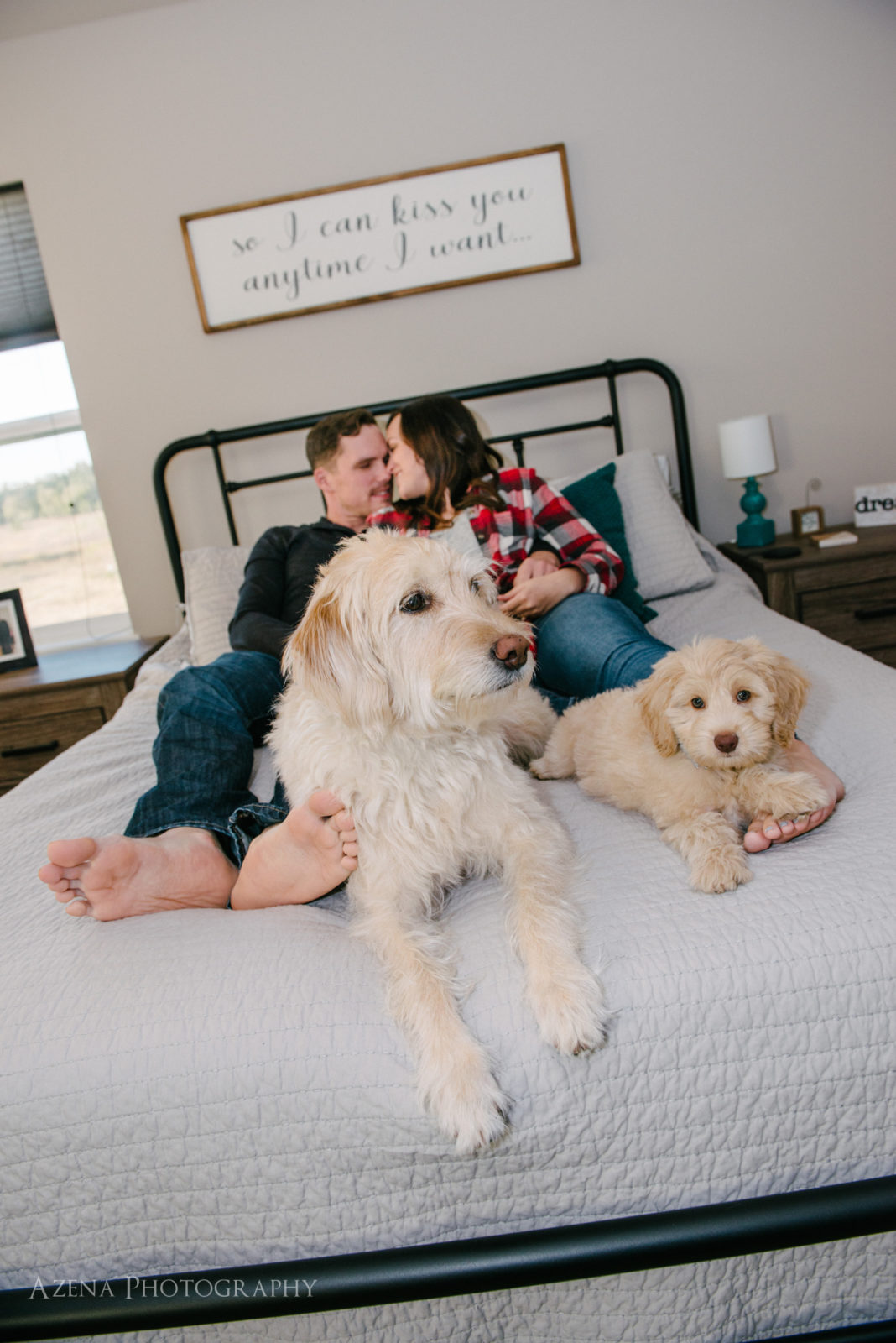 engaged couple kissing in bed with puppies