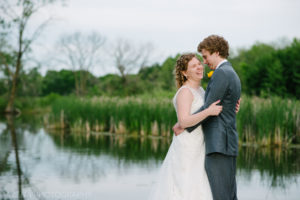 bride and groom laughing by a lake